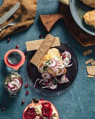 Запеченные куриные бедрышки с маринованным красным луком, зернами граната и цельнозерновыми хлебцами