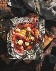 Лангустины и морские гребешки, запеченные в фольге на подушке из картофеля